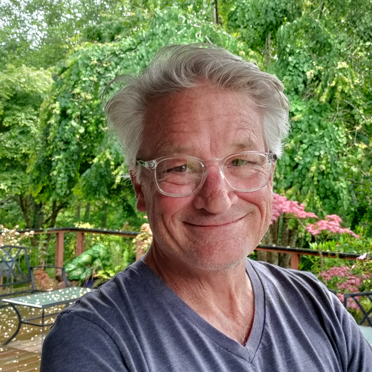 a man wearing glasses and smiling at the camera
