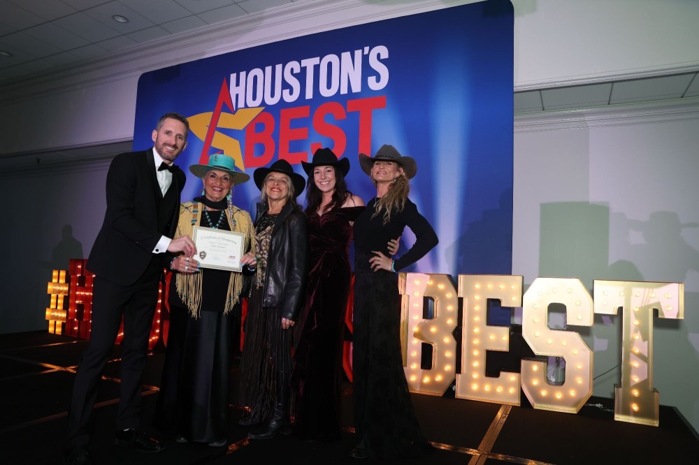 Five people on a stage holding a certificate with 'Houston's Best' and large lit letters spelling 'BEST'.